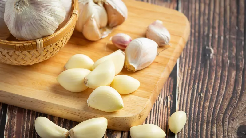 Close-up tumpukan bawang putih segar dengan kulit putih bersih yang menggambarkan sumber alami antioksidan dan antibakteri, siap digunakan dalam pengobatan atau masakan